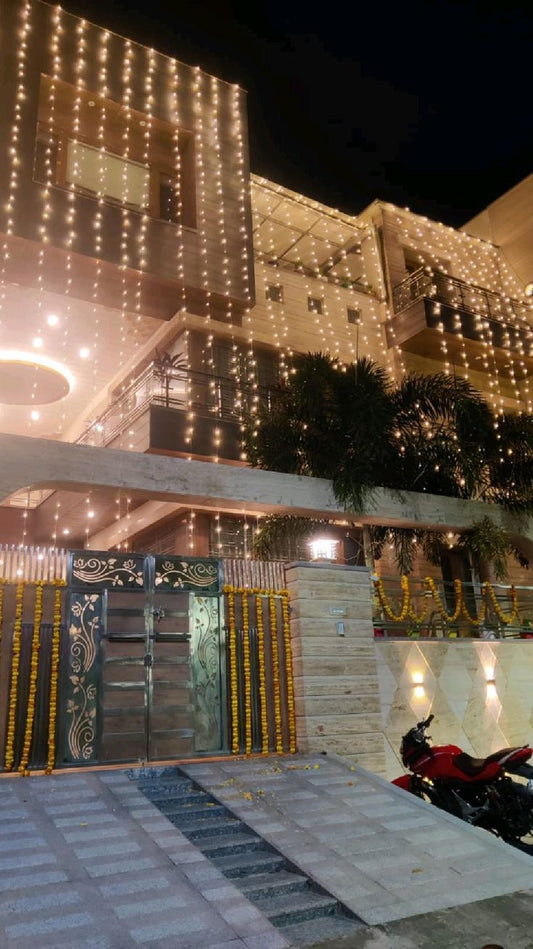 A house facade illuminated with cascading LED lights, creating a festive and elegant appearance for an event or holiday season.