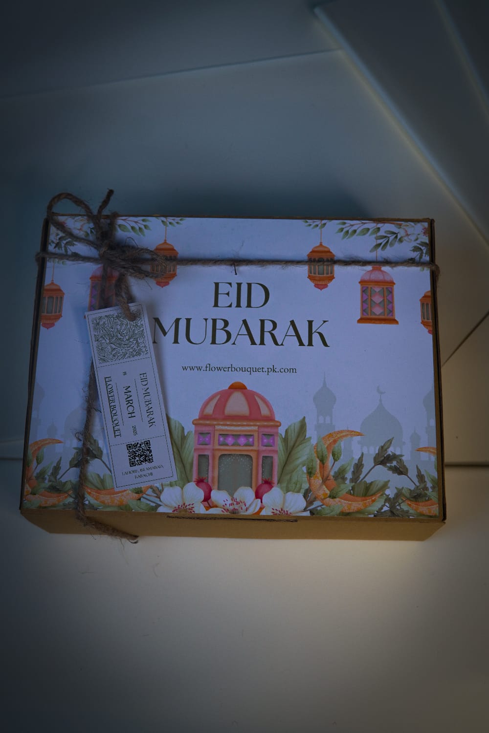 Flat lay of Eid gift box for boys featuring perfume, chocolates, and printed photos