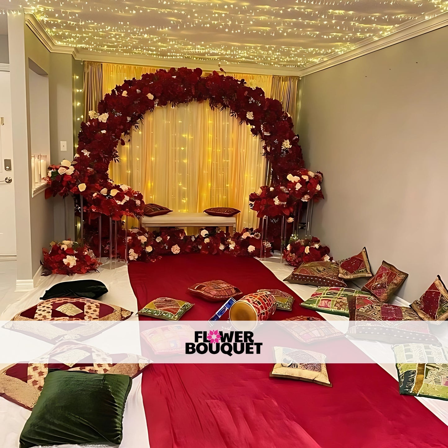 Indoor Mehndi decor with a red floral arch, fairy lights, a red carpet, and traditional cushions for a luxurious and festive setup.