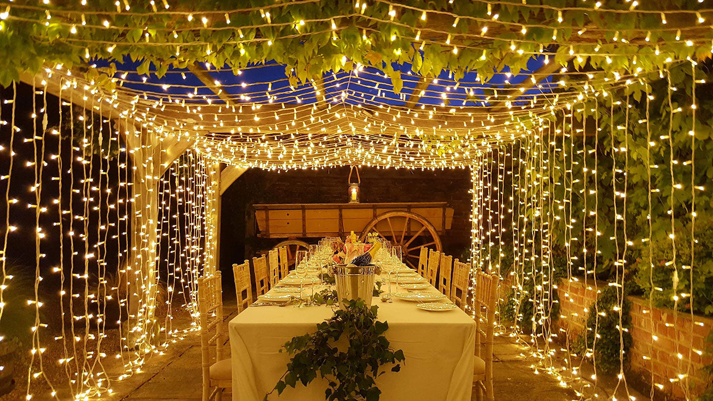 Outdoor dining area adorned with twinkling LED string lights, creating a magical atmosphere for a wedding celebration.