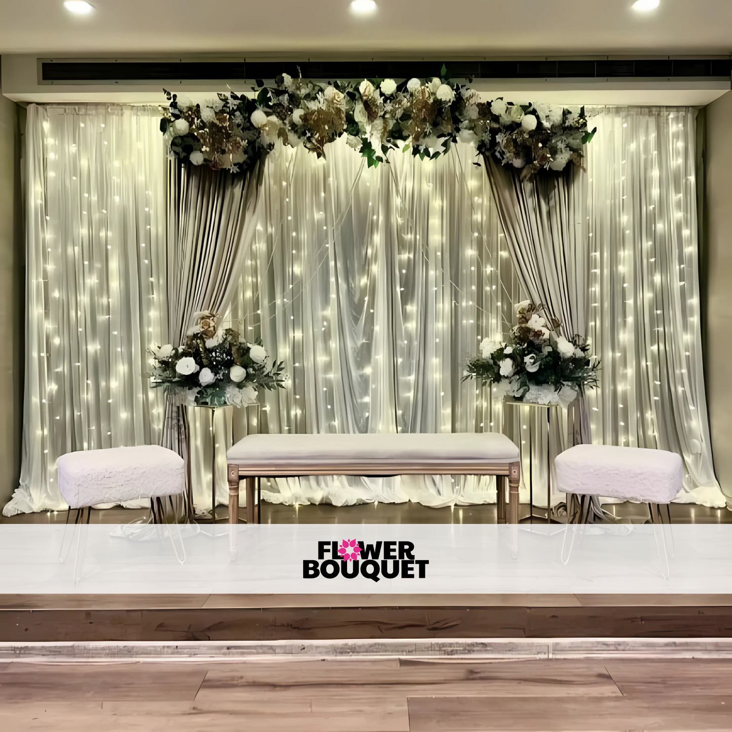 Minimalist wedding stage with a silver draped backdrop, cascading fairy lights, white floral arrangements, and modern seating, perfect for intimate events