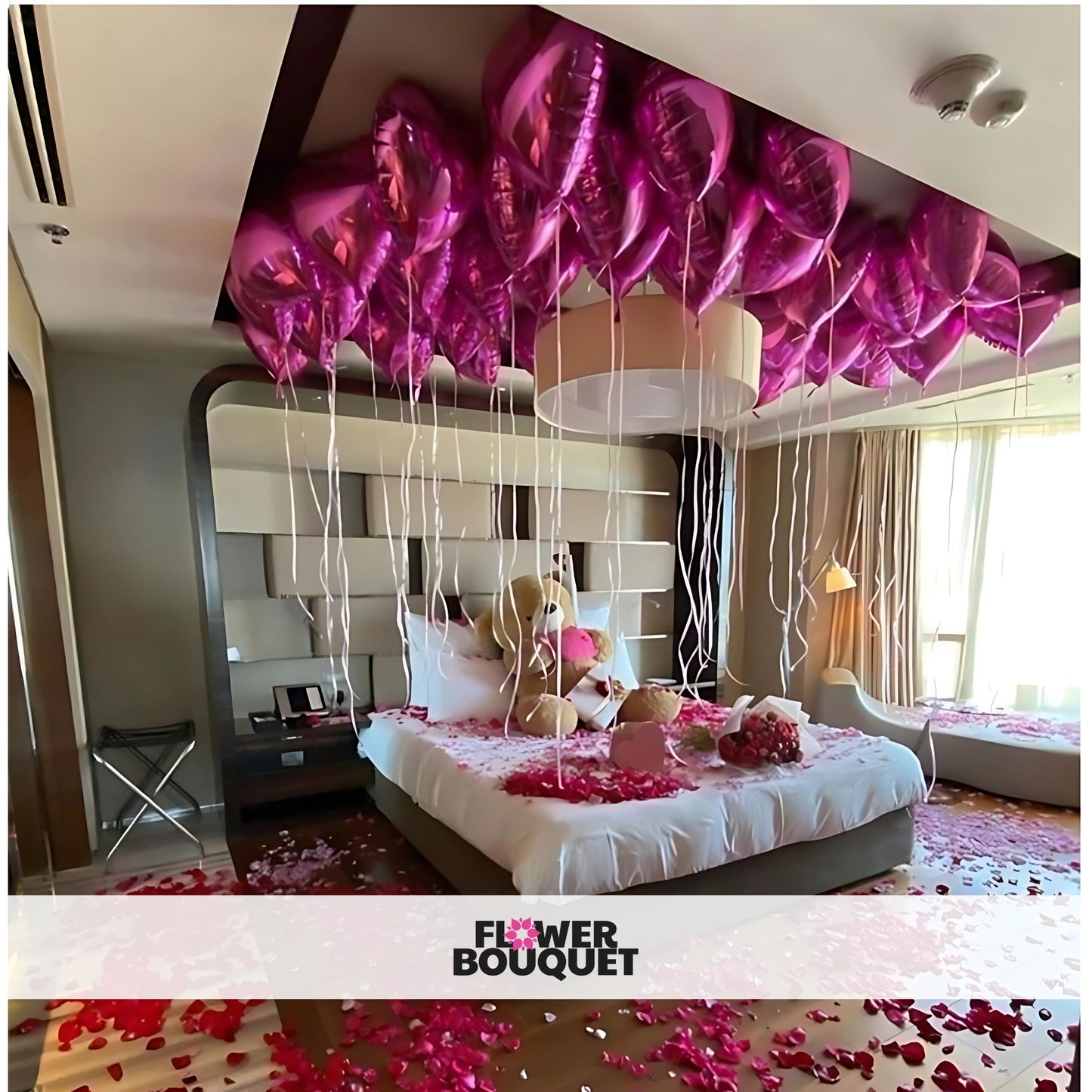 Romantic room decoration with pink rose petals, pink heart-shaped balloons, and a large teddy bear creating a dreamy and loving atmosphere.