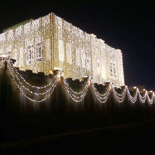 A house beautifully decorated with cascading LED lights covering the exterior walls, creating a sparkling effect.