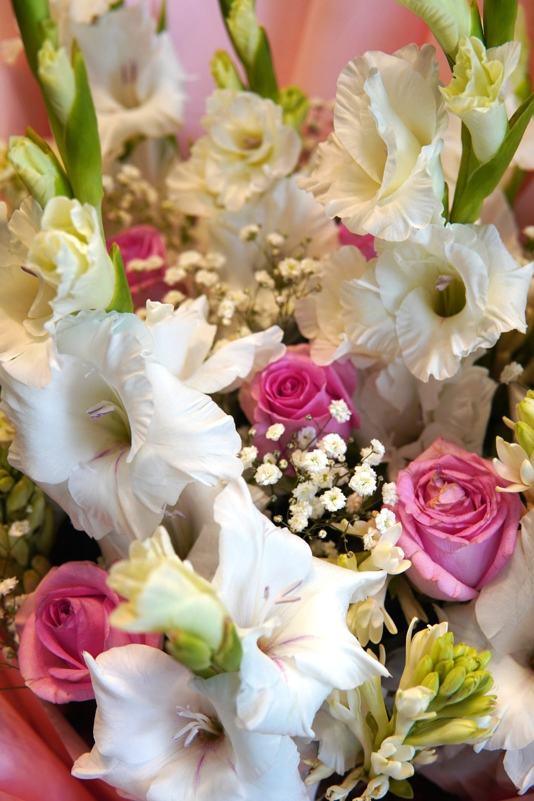 Large hand-tied bouquet with soft white gladiolus, pink and cream roses, and baby's breath