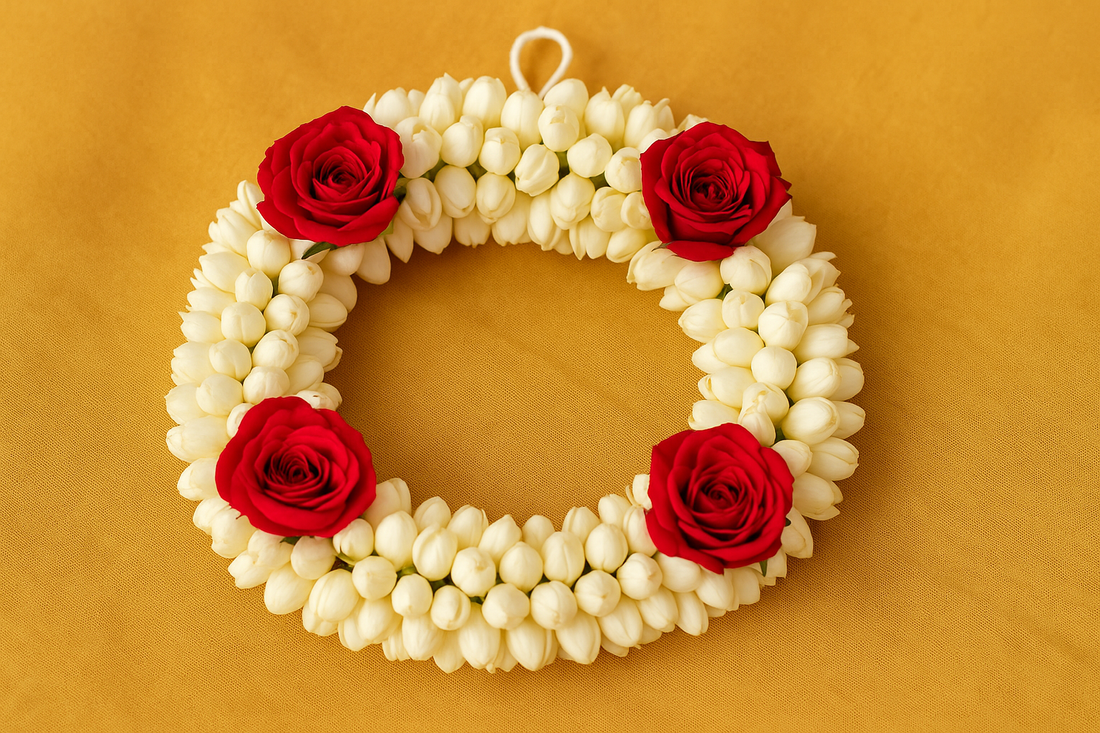 “Traditional gajra made with fresh white jasmine buds and red roses, arranged in a circular floral bracelet style on a golden festive fabric background.”