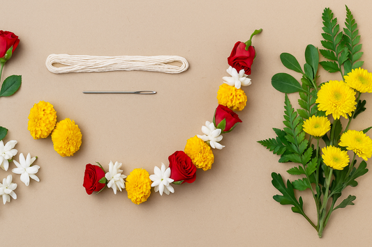 “Fresh flower garland in progress with red roses, jasmine, marigolds, chrysanthemums, thread, and needle arranged on a neutral background – step-by-step guide by FlowerBouquet.pk”