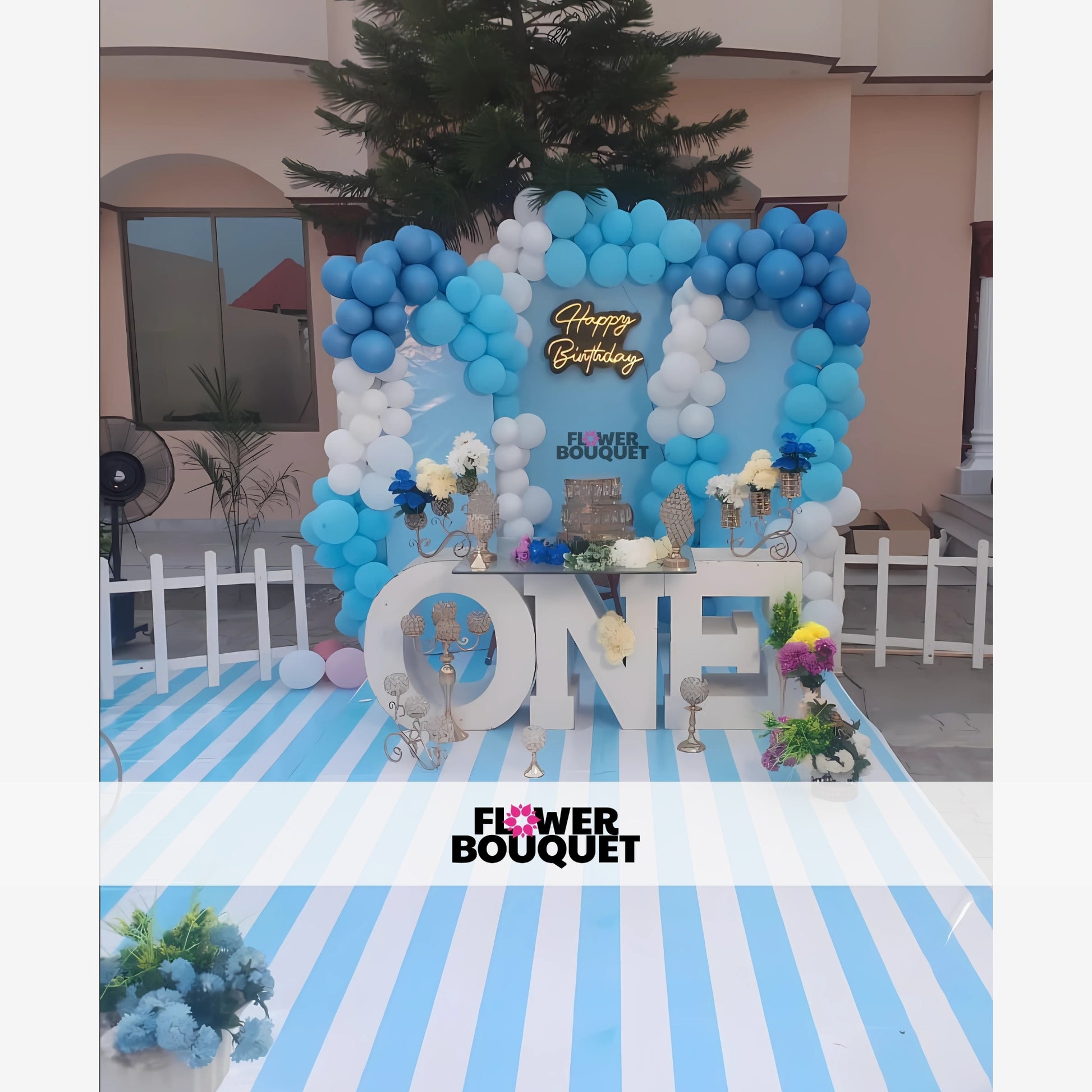 Birthday party setup with a blue and white color theme, featuring a balloon arch and a "Happy Birthday" sign.