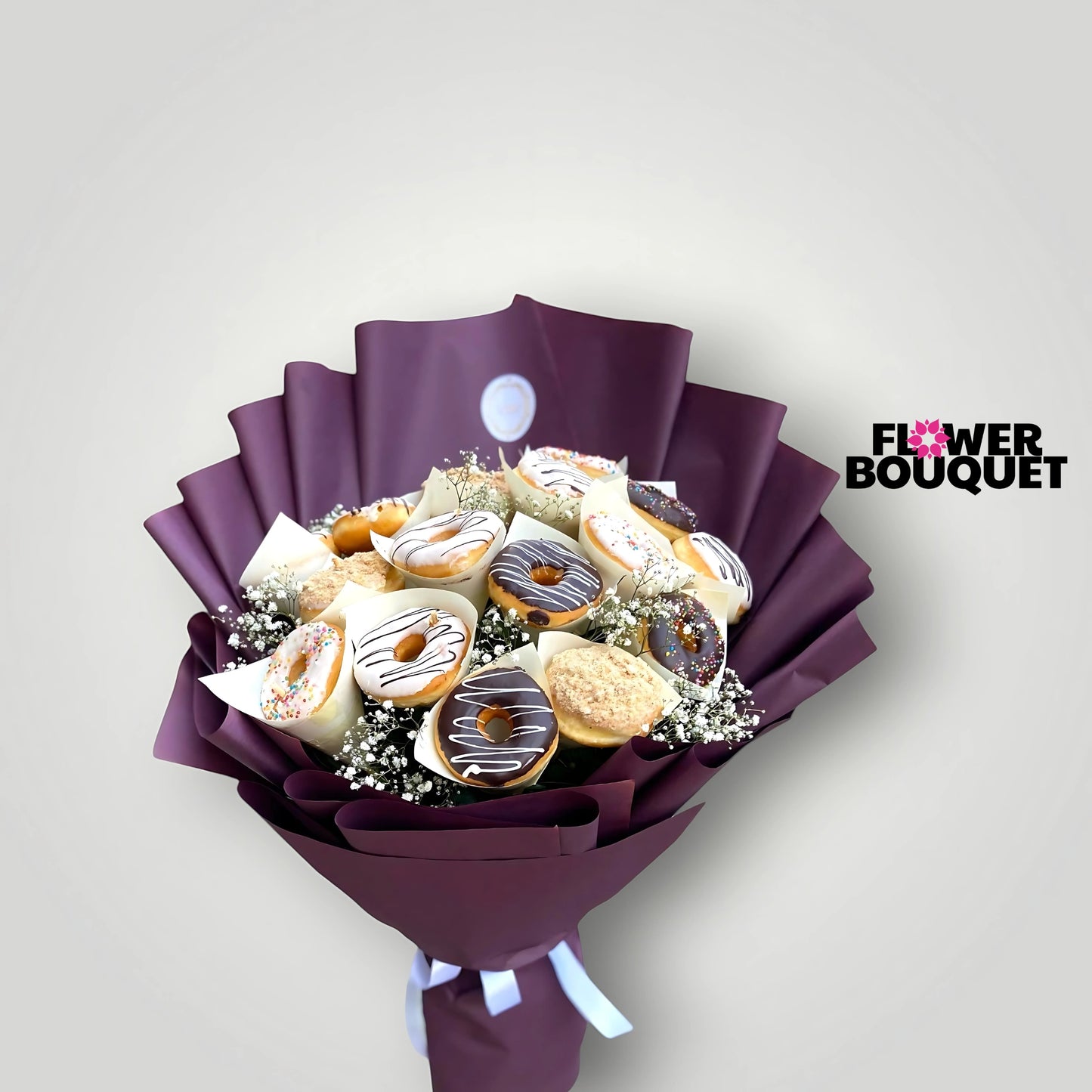 A bouquet of gourmet donuts in various flavors and toppings, including chocolate drizzle and sprinkles, arranged with delicate baby's breath and wrapped in a luxurious purple paper for a sophisticated and indulgent presentation.