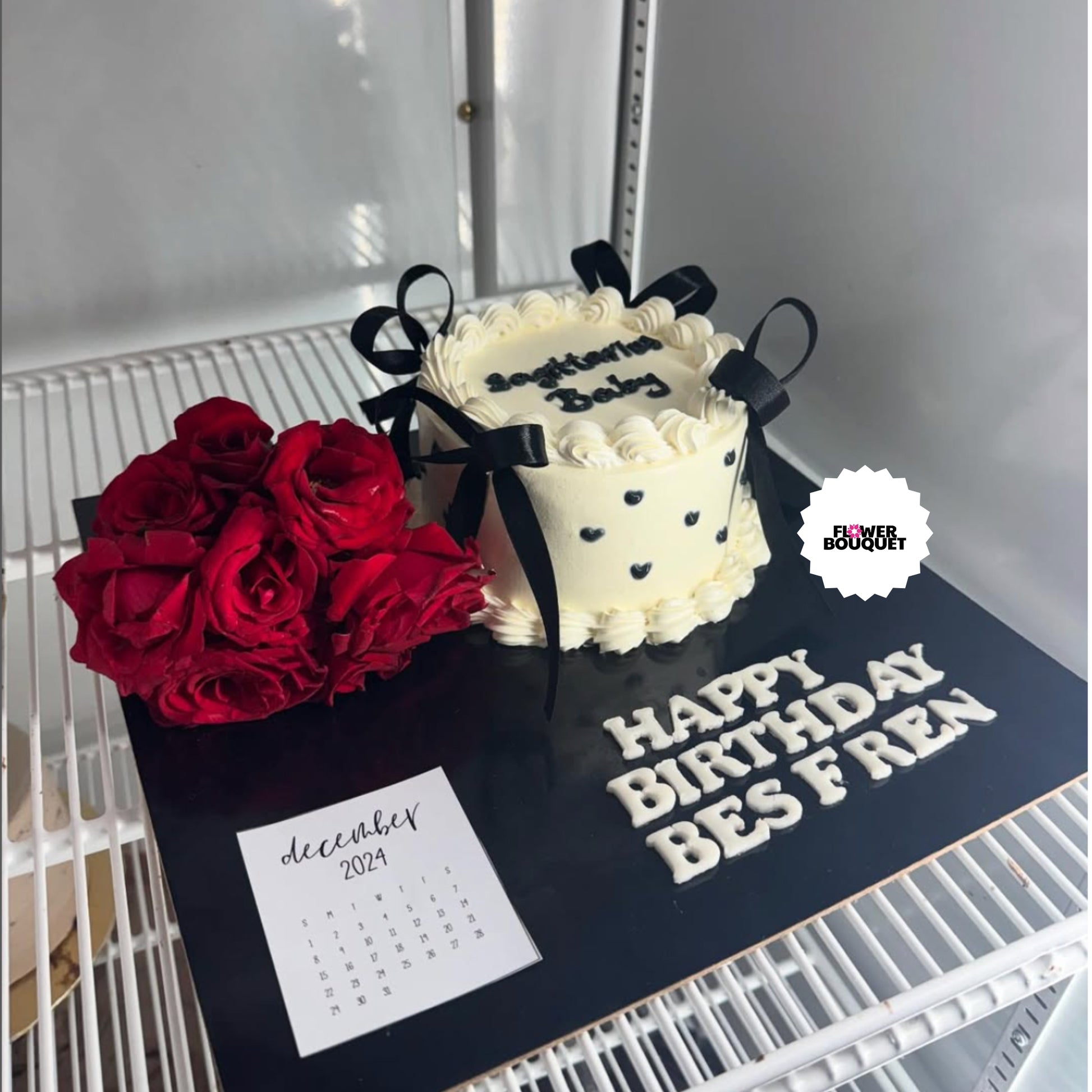 Cream cake with black bows, red roses, and "Happy Birthday Besfriend" message on black board with December calendar.