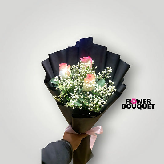 Elegant black wrapped bouquet of pink-tipped roses and baby's breath with a pink ribbon.