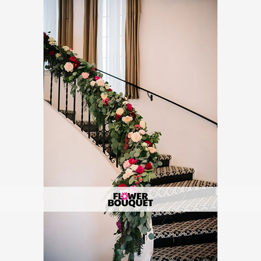 Elegant floral garland with green foliage and vibrant pink, white, and red flowers draping along a staircase railing, perfect for weddings and event décor.