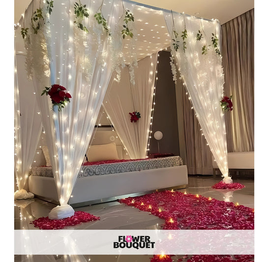 Enchanted Flower Canopy Bed Decor with white drapes, fairy lights, red and white flowers, and rose petals.