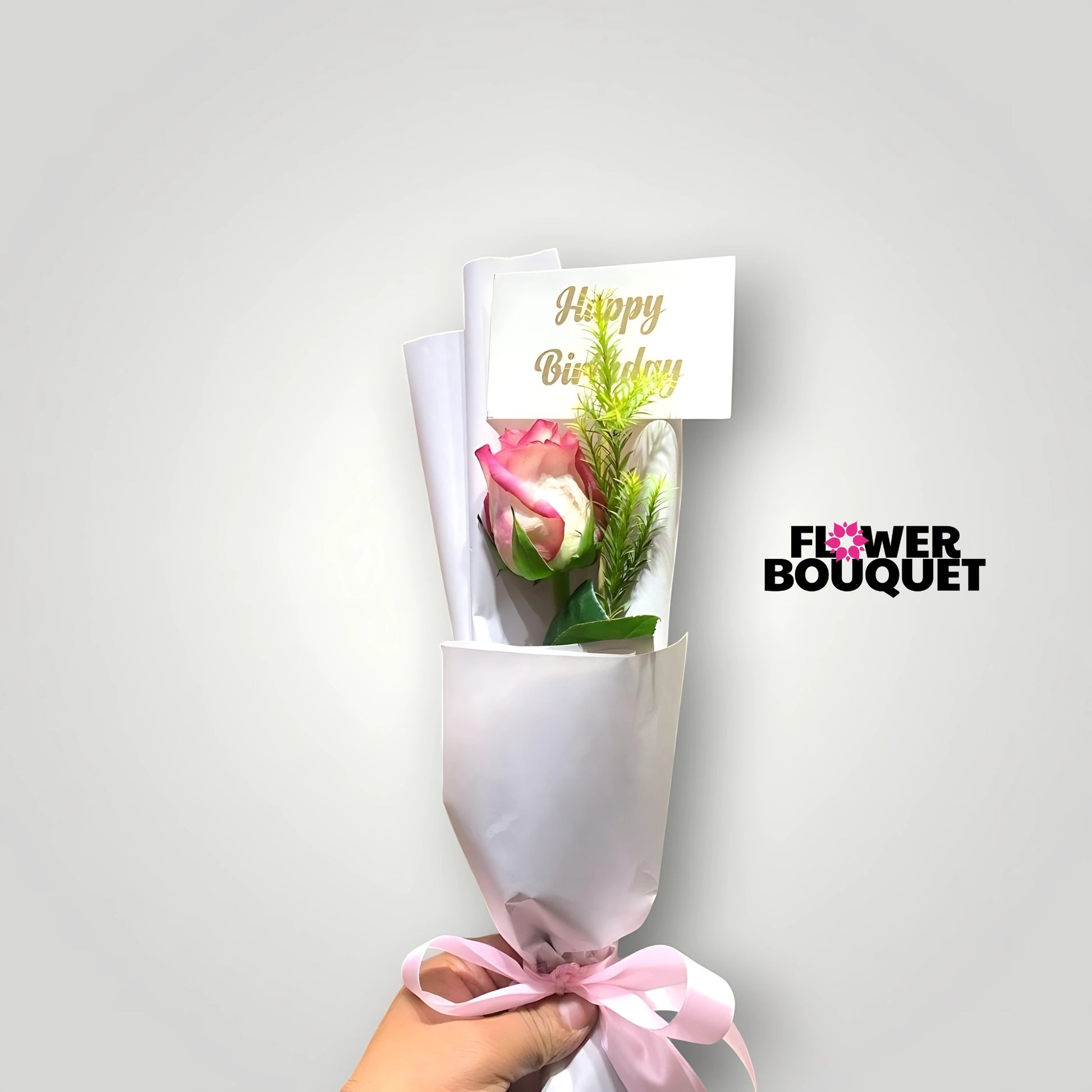 Vibrant pink rose surrounded by lush green foliage, presented in a simple, elegant wrapping with a "Happy Birthday" message for a heartfelt birthday bouquet.