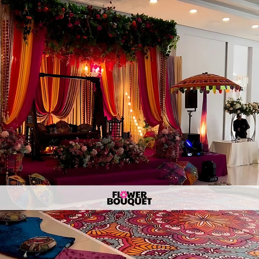 Traditional wooden swing adorned with colorful drapes and surrounded by floral arrangements, vibrant floor cushions, and a decorative umbrella for a Mehndi event.