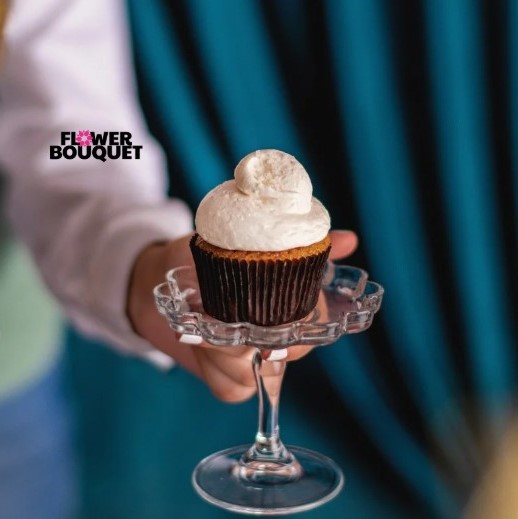 A luxurious Raffaello Cupcake with creamy coconut frosting, shredded coconut, and a signature Raffaello candy on top, perfect for gifting or celebrations.