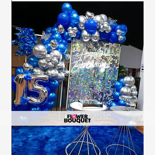 Decorative setup for a 15th birthday celebration with a shimmering backdrop, neon "Happy Birthday" sign, and balloon arrangements.